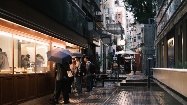 亮灯小店旁撑伞或站立的人。