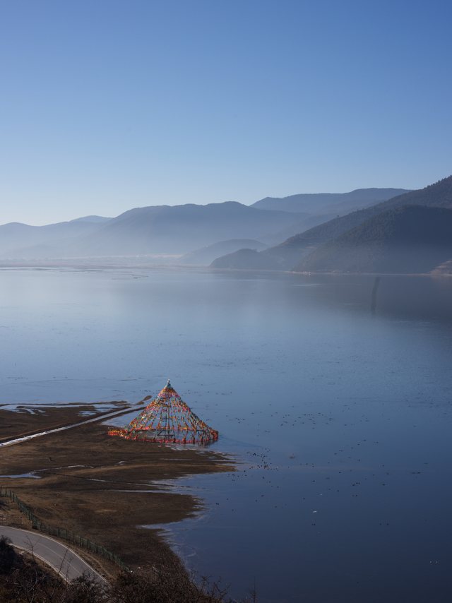 安静湖面、近处浅滩与层叠远山。