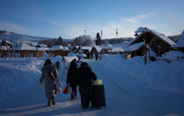 雪地村落里提着行李行走的人。