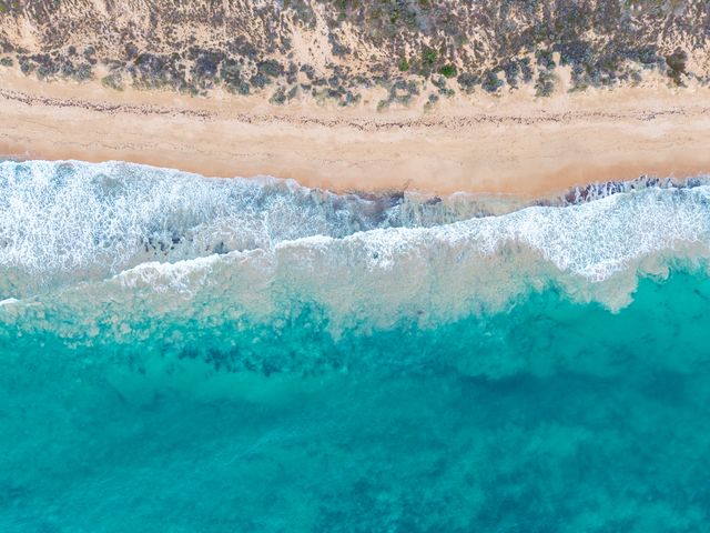 浪线、沙滩与蓝绿色海水的俯视航拍。